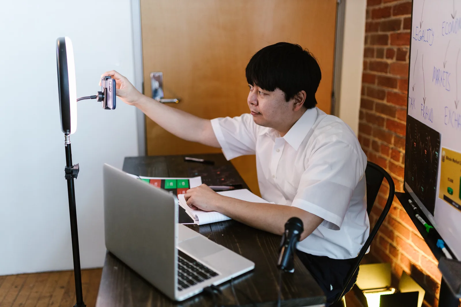 Vlogger recording content with a smartphone and ring light, showcasing an interactive workspace.